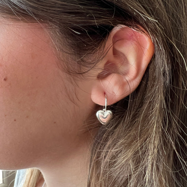 Close-up of an ear wearing a small earring with hair partially covering it.