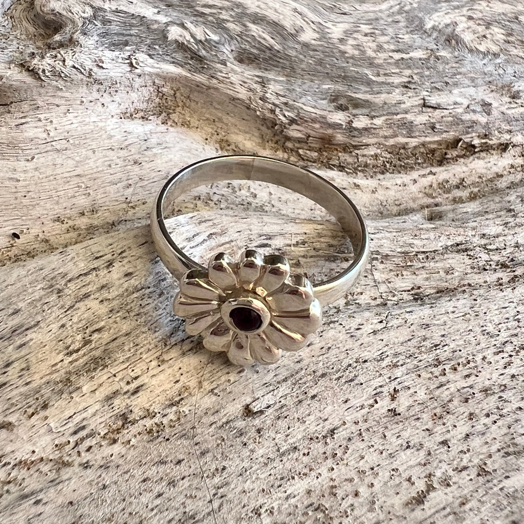 Silver ring with a floral design on a wooden surface