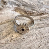 Silver ring with a floral design on a wooden surface