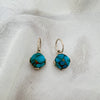 Pair of turquoise earrings on a white fabric background