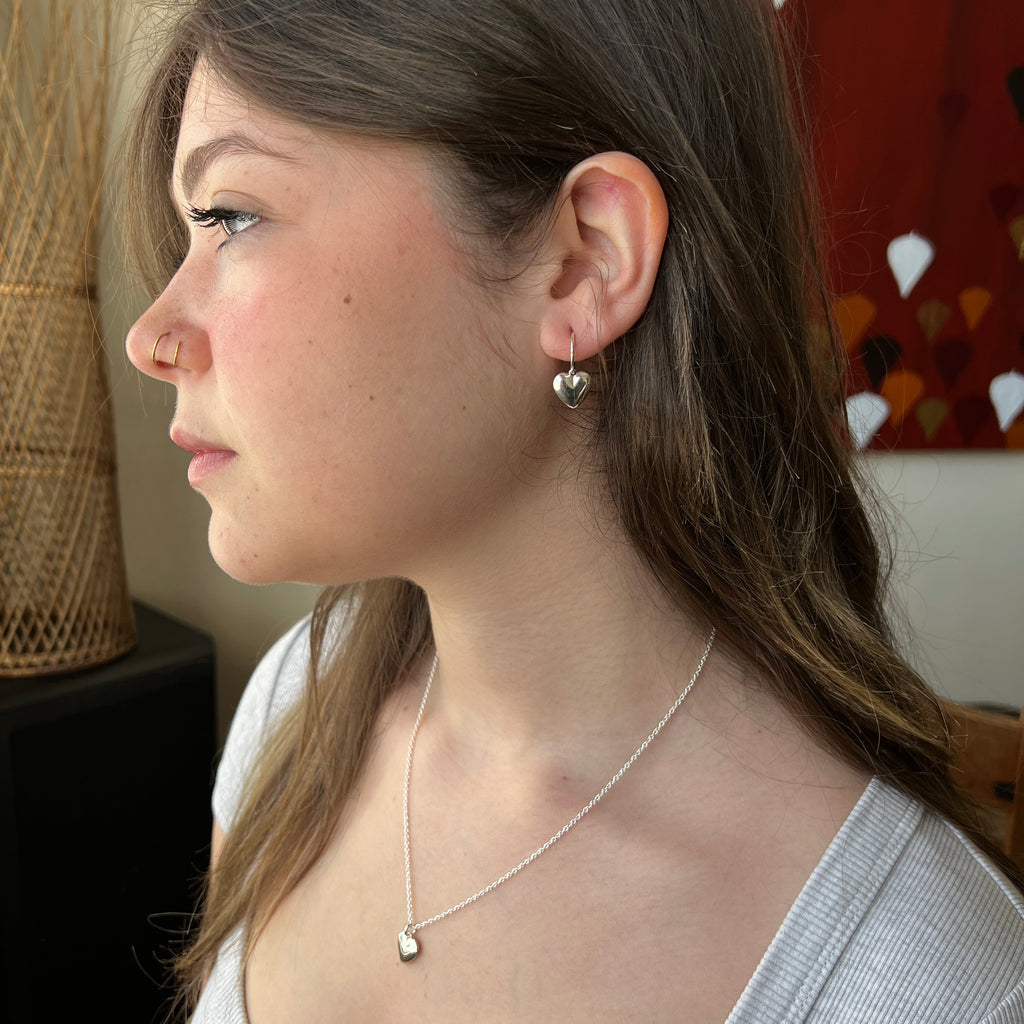 Close-up of a woman wearing a necklace and earrings indoors.