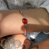 Silver bracelet with a red stone on a wrist with tattoos