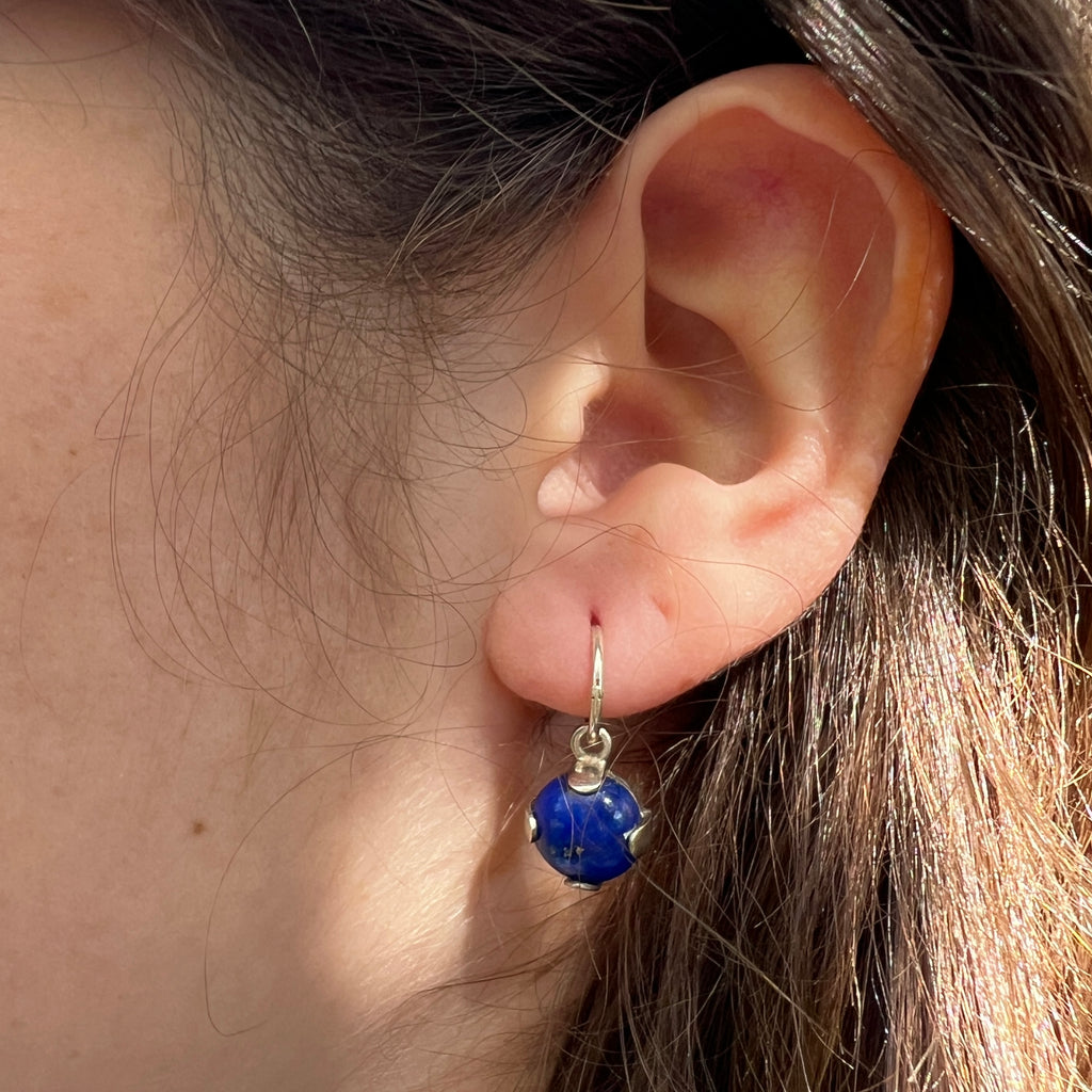 Close-up of an ear wearing a blue gemstone earring.