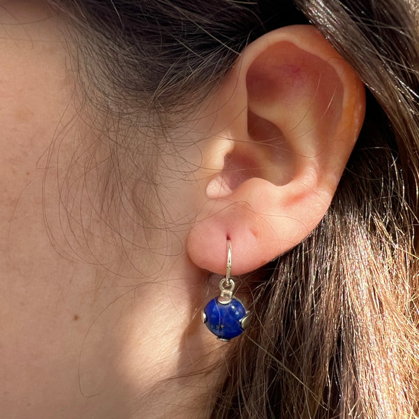 Close-up of an ear wearing a blue gemstone earring.