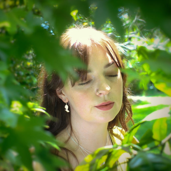 Woman with eyes closed surrounded by green leaves