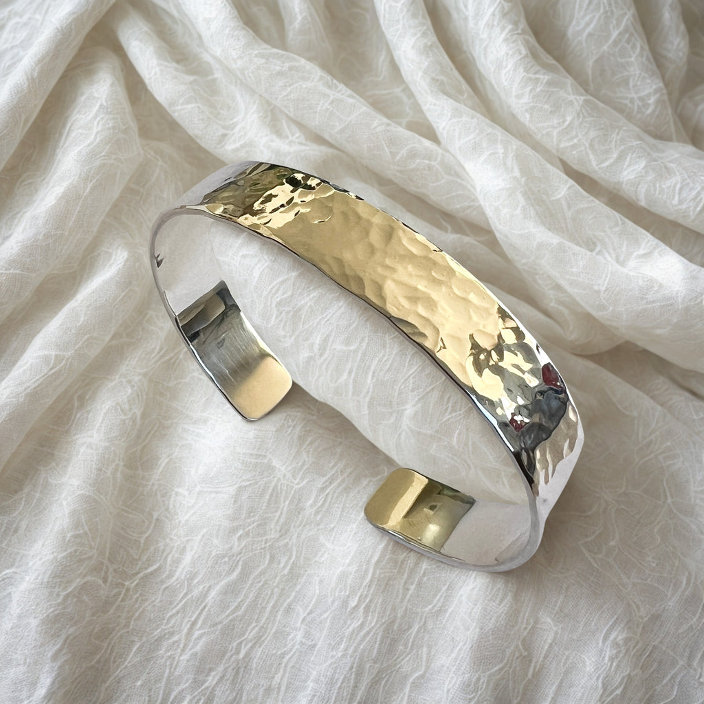 Silver cuff bracelet on a white fabric background