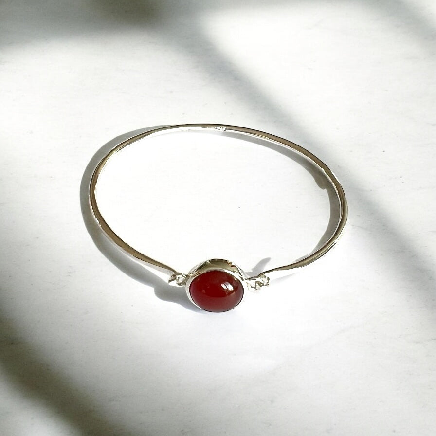 Silver bracelet with red stone on white background
