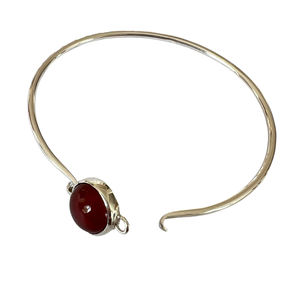 Silver bracelet with a red stone on a white background