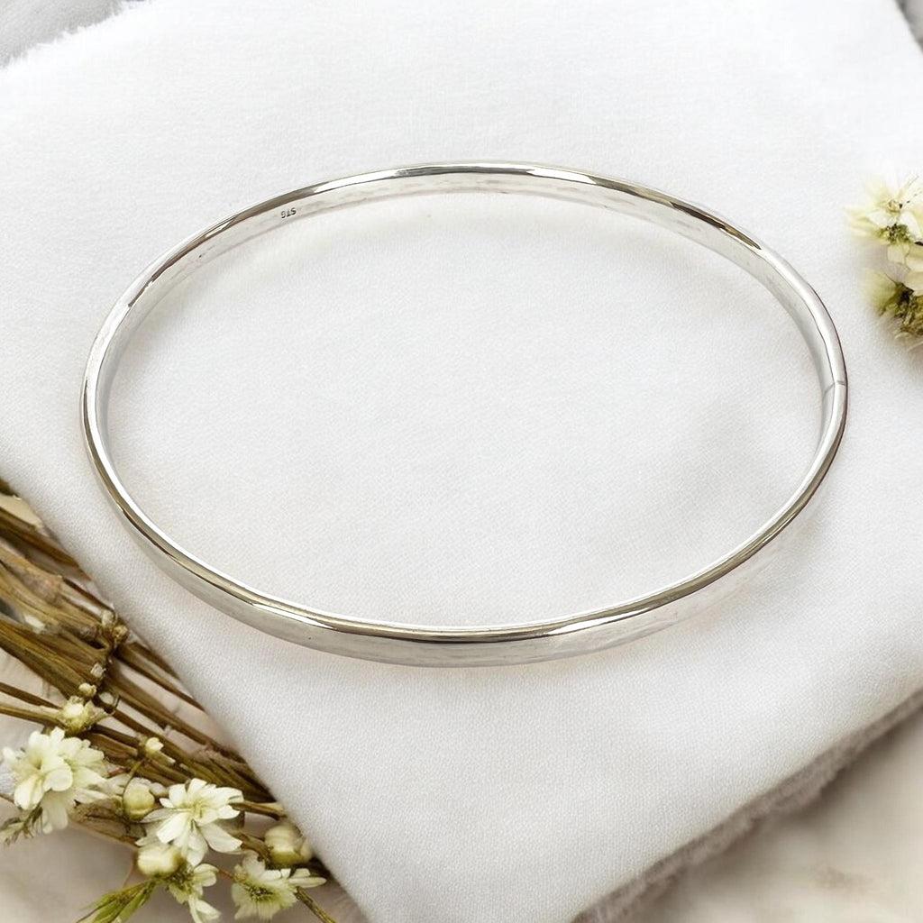 Silver bracelet on a white fabric background with delicate flowers