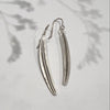 Silver feather-shaped earrings on a light gray background