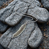 Silver feather necklace on gray stones