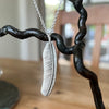 Silver feather pendant necklace on a blurred background