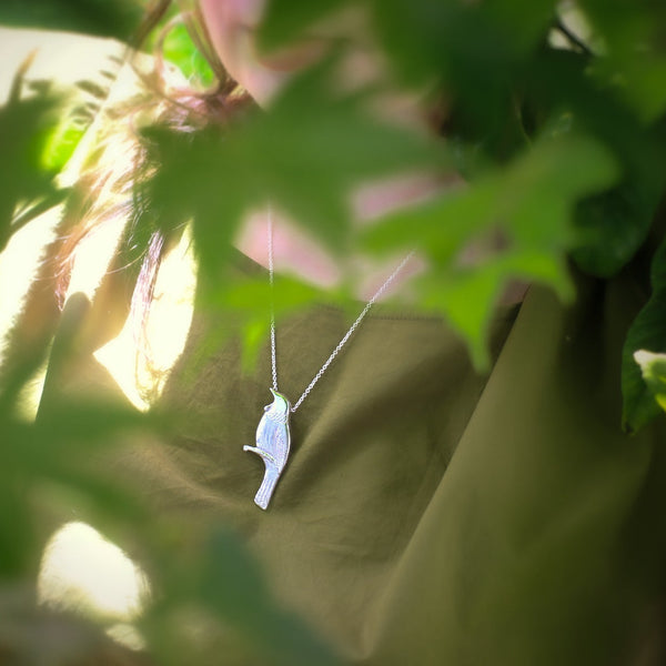 Person wearing a Tui necklace with a blurred green background
