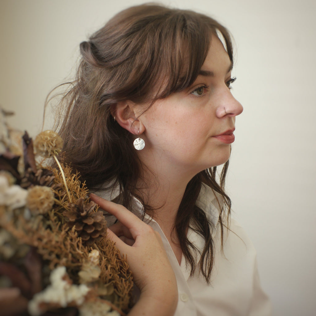 Woman holding dried flowers against a plain background