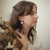 Woman holding dried flowers against a plain background
