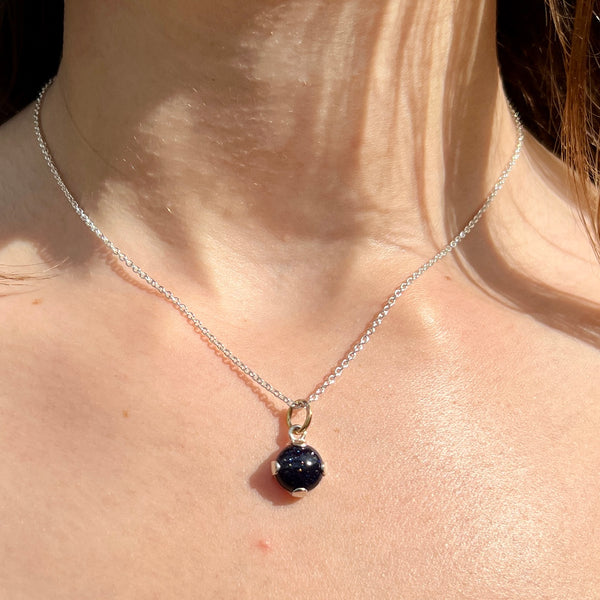 Necklace with a dark blue pendant on a person's neck