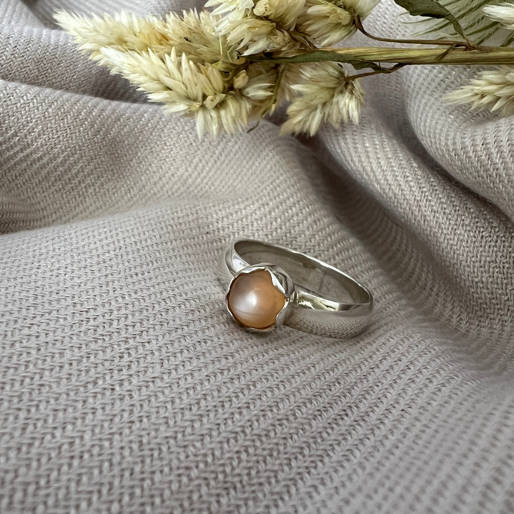 Silver ring with a brown stone on a textured gray fabric background