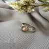 Silver ring with a brown stone on a textured gray fabric background