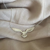 Silver cook's petrel necklace resting on fabric background
