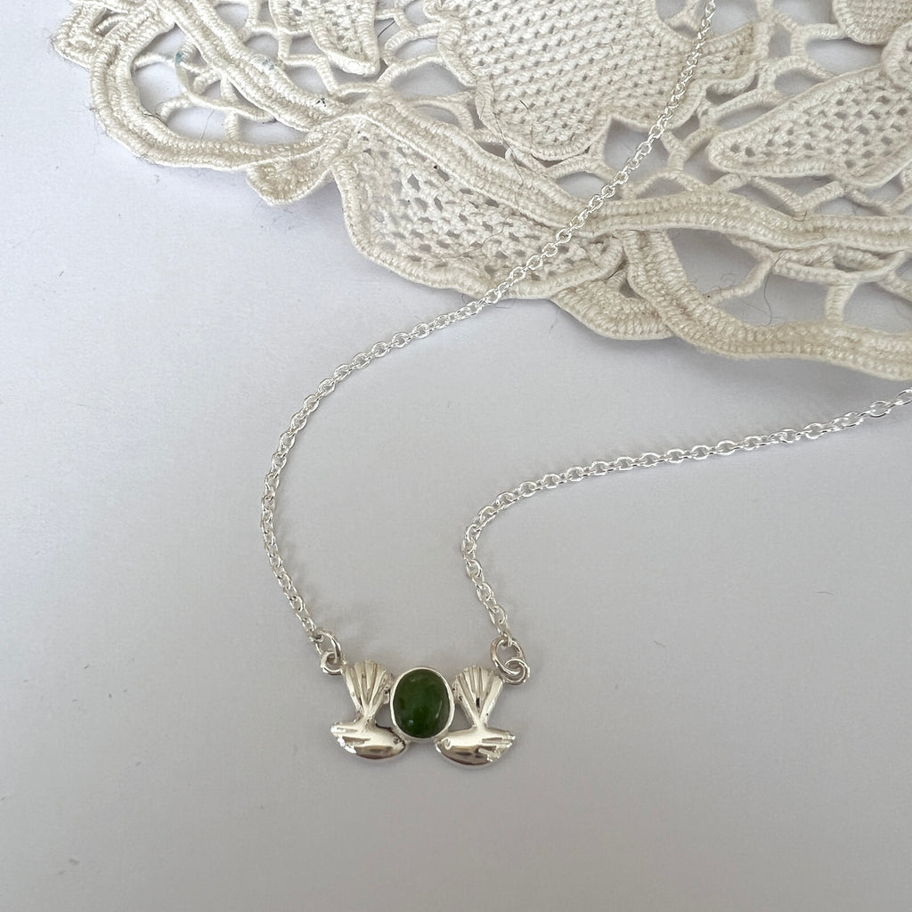 Silver necklace with a green stone pendant on a white background