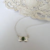 Silver necklace with a green stone pendant on a white background