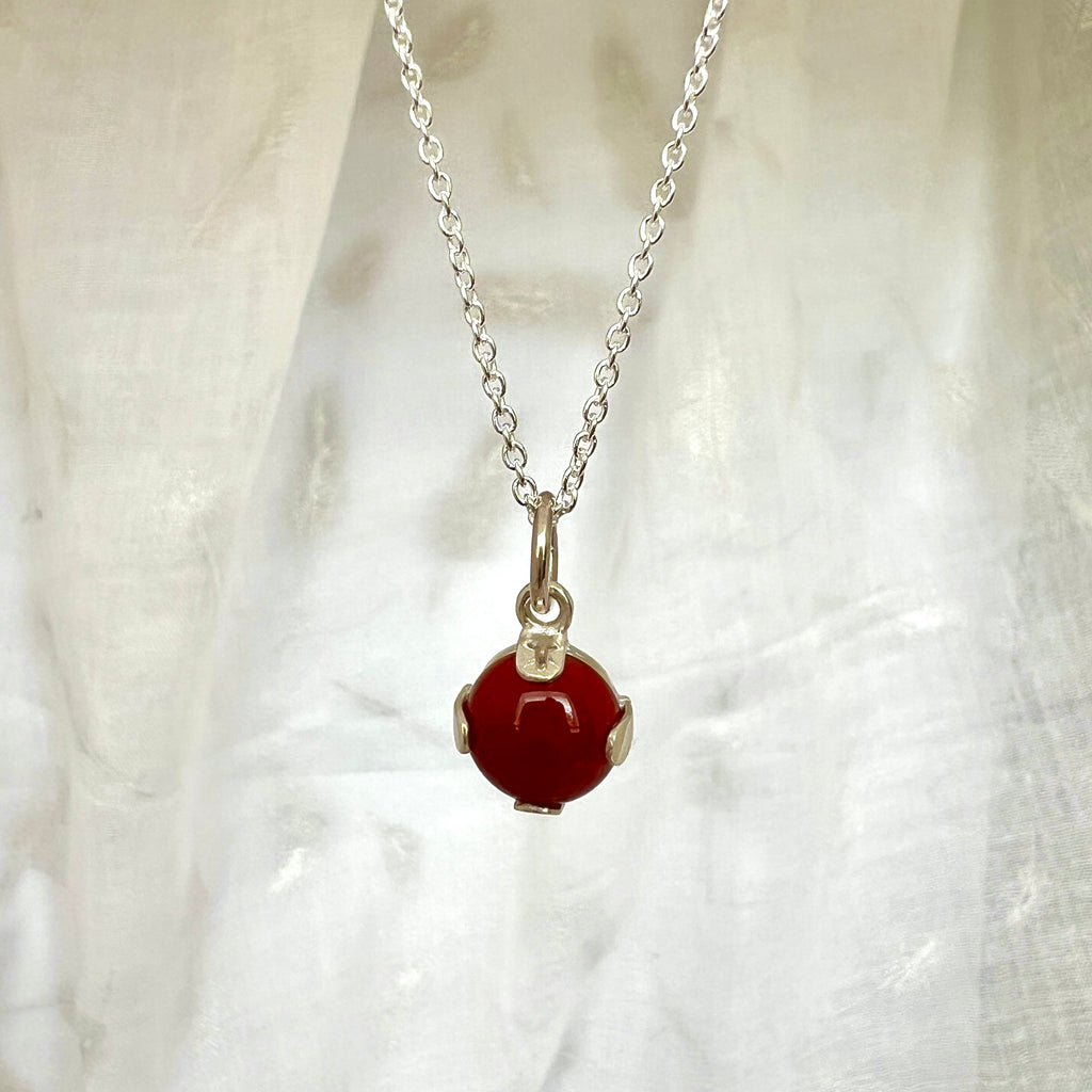 Red gemstone necklace against white fabric