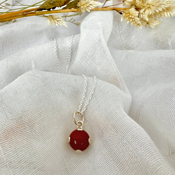 Red gemstone necklace against white fabric