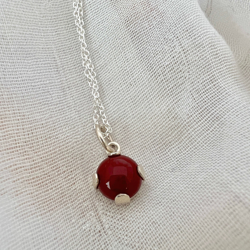 Necklace with a red pendant on a white fabric background