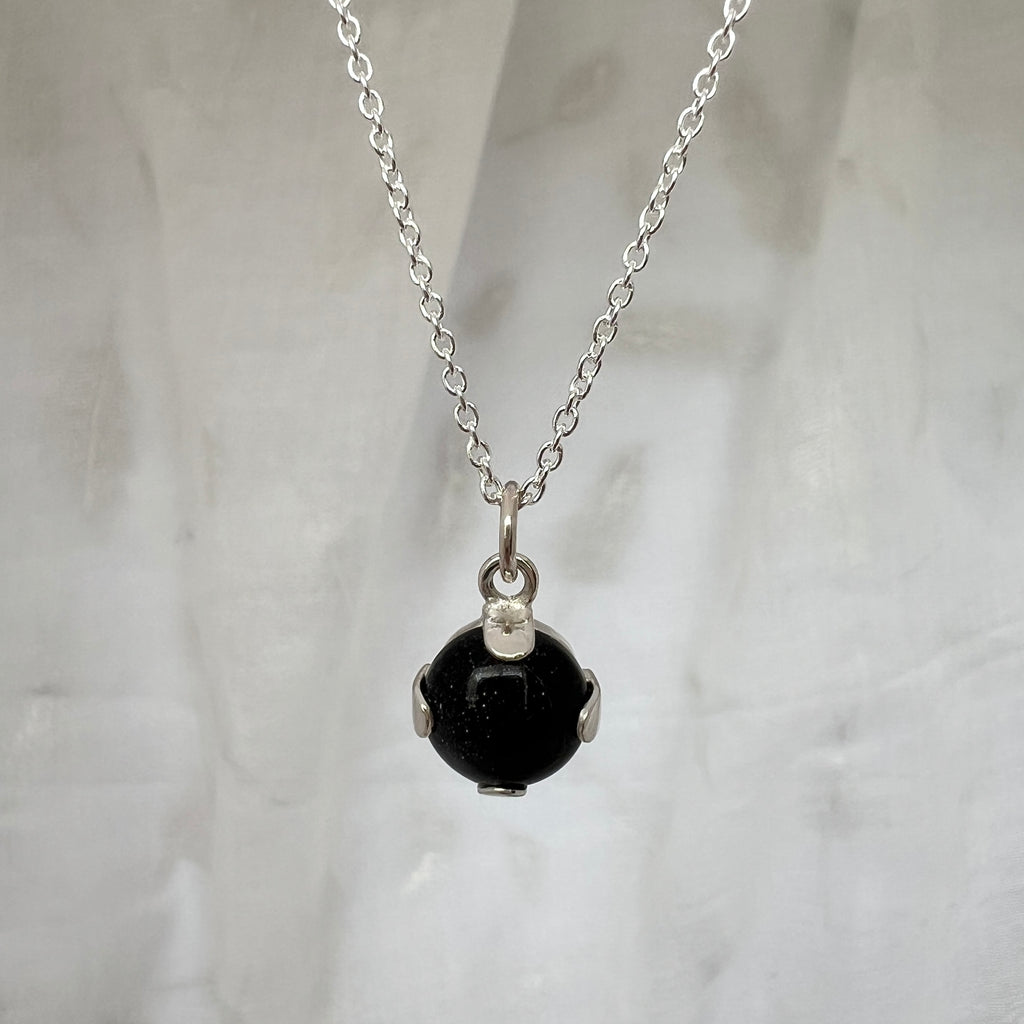 Necklace with a deep blue gemstone pendant on a light gray background