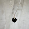 Necklace with a deep blue gemstone pendant on a light gray background