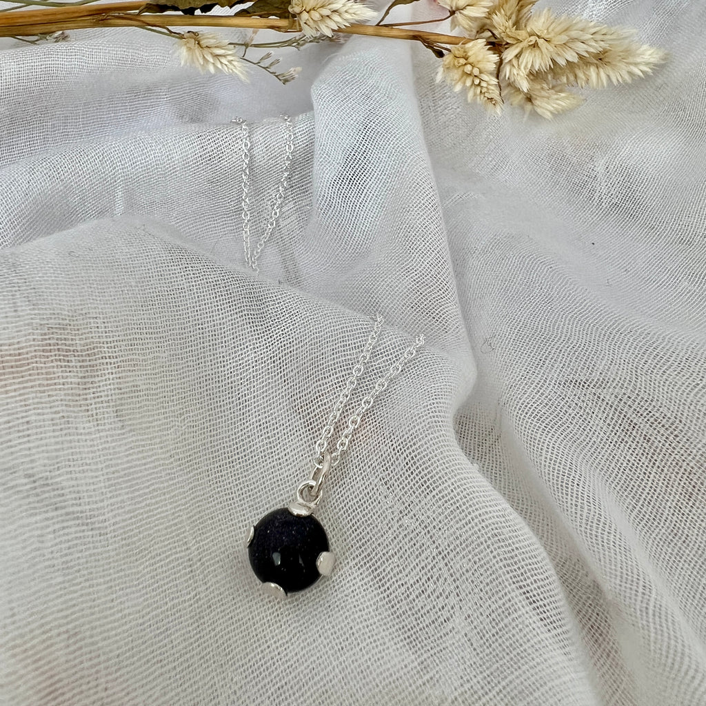 Necklace with adrak blue pendant on a white fabric background