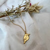 Gold necklace with a kingfisher bird pendant on a white fabric background