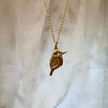 Gold bird-shaped pendant necklace on a light fabric background