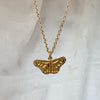 Gold butterfly necklace on a light gray background