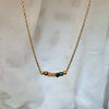Necklace with small beads on a gold chain against a white fabric background