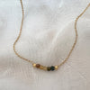 Necklace with small beads on a gold chain against a textured white background