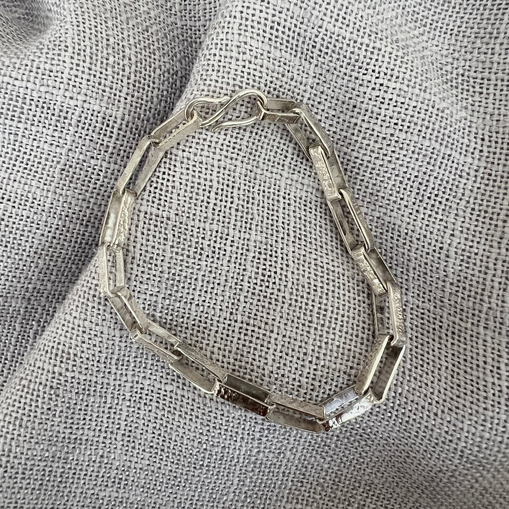 Silver bracelet on a textured gray fabric background