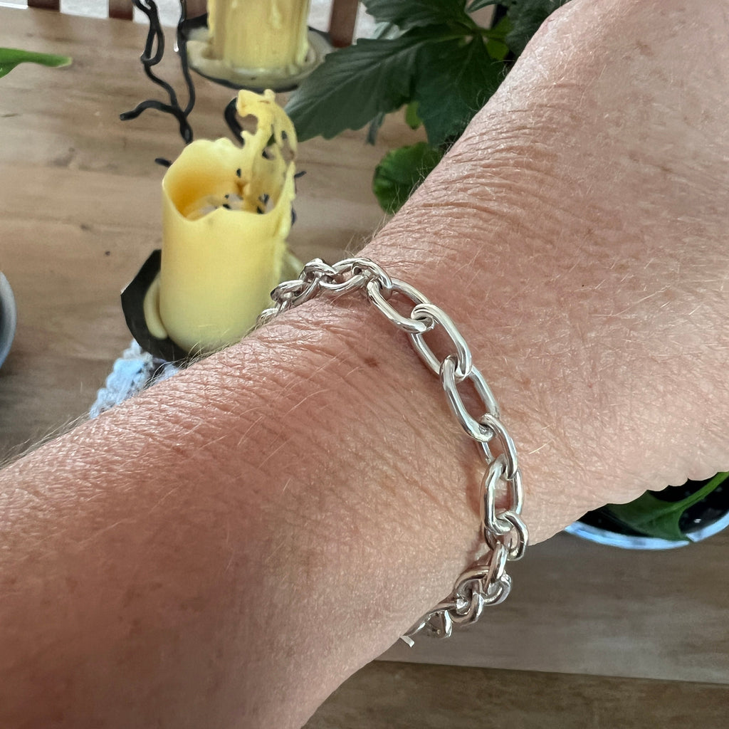 Silver chain bracelet on a wrist with a blurred background