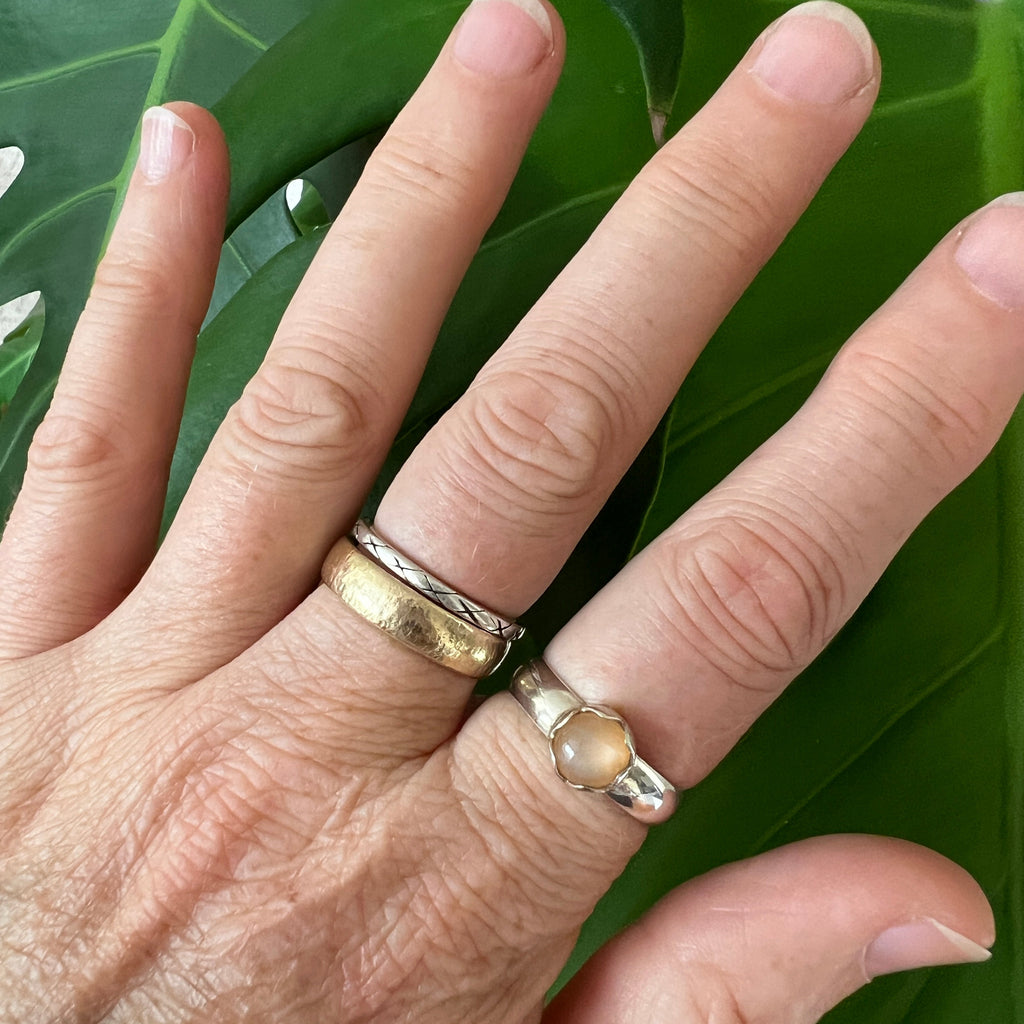 Hand with two rings on a green leaf background