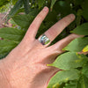 Hand with a ring on a leafy background