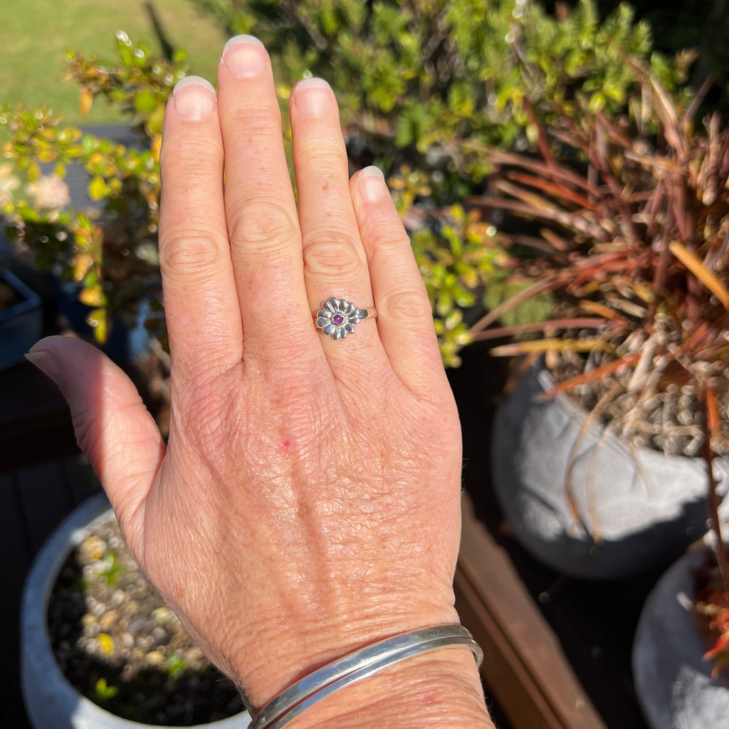 Hand wearing a ring with a decorative design outdoors