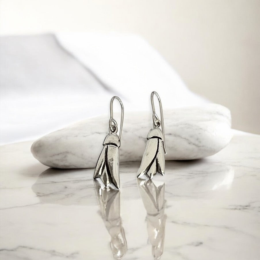 Silver Kowhai flower earrings on a marble surface