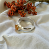 Silver ring with a brown stone on a beige fabric background