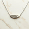 Silver necklace with a half-circle pendant on a marble surface