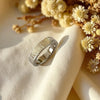 Silver ring on a beige fabric with yellow flowers in the background
