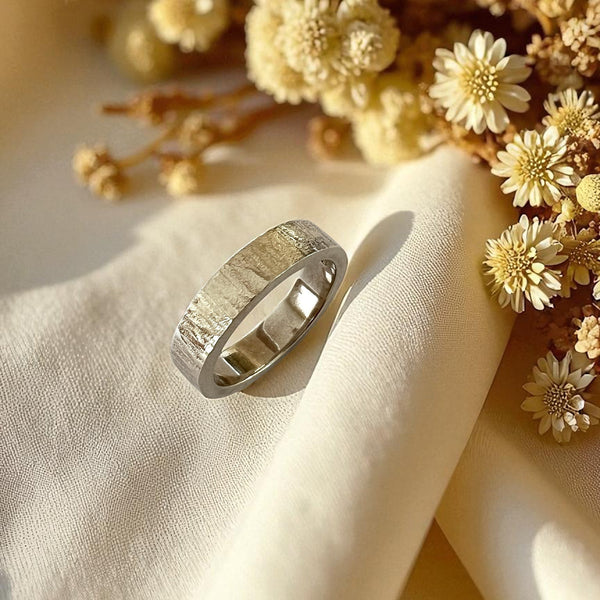Silver ring on a beige fabric with yellow flowers in the background