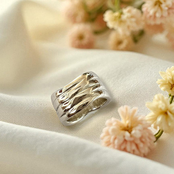 Silver ring on a white fabric background with pink flowers