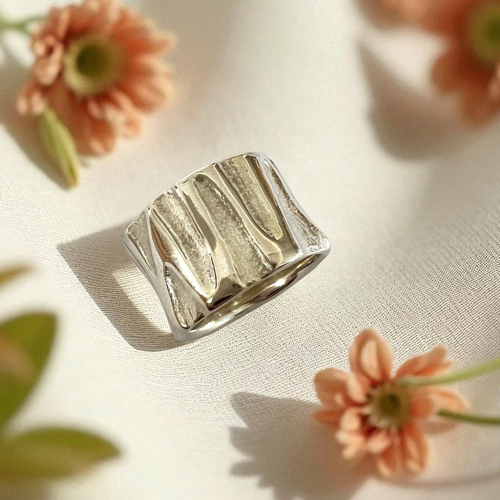 Silver ring with a ribbed texture on a light background with flowers