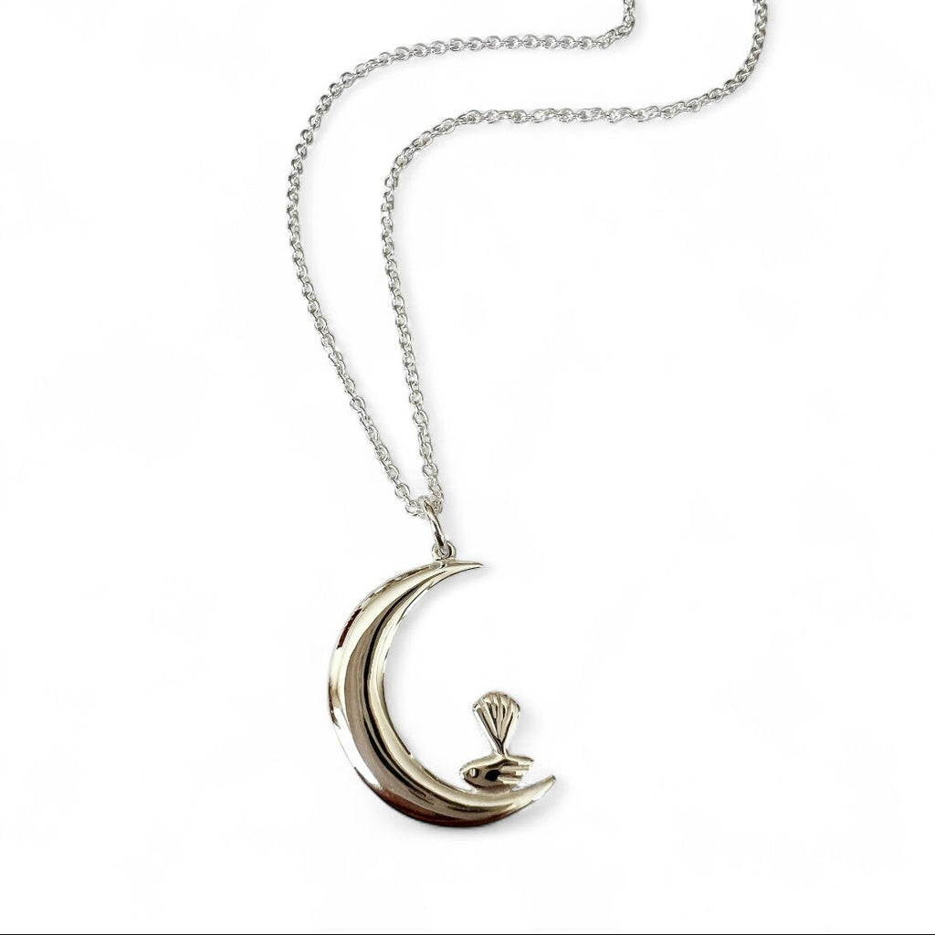 Silver necklace with a crescent moon and bird pendant on a white background