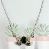 Silver necklace with a green stone on a light gray background